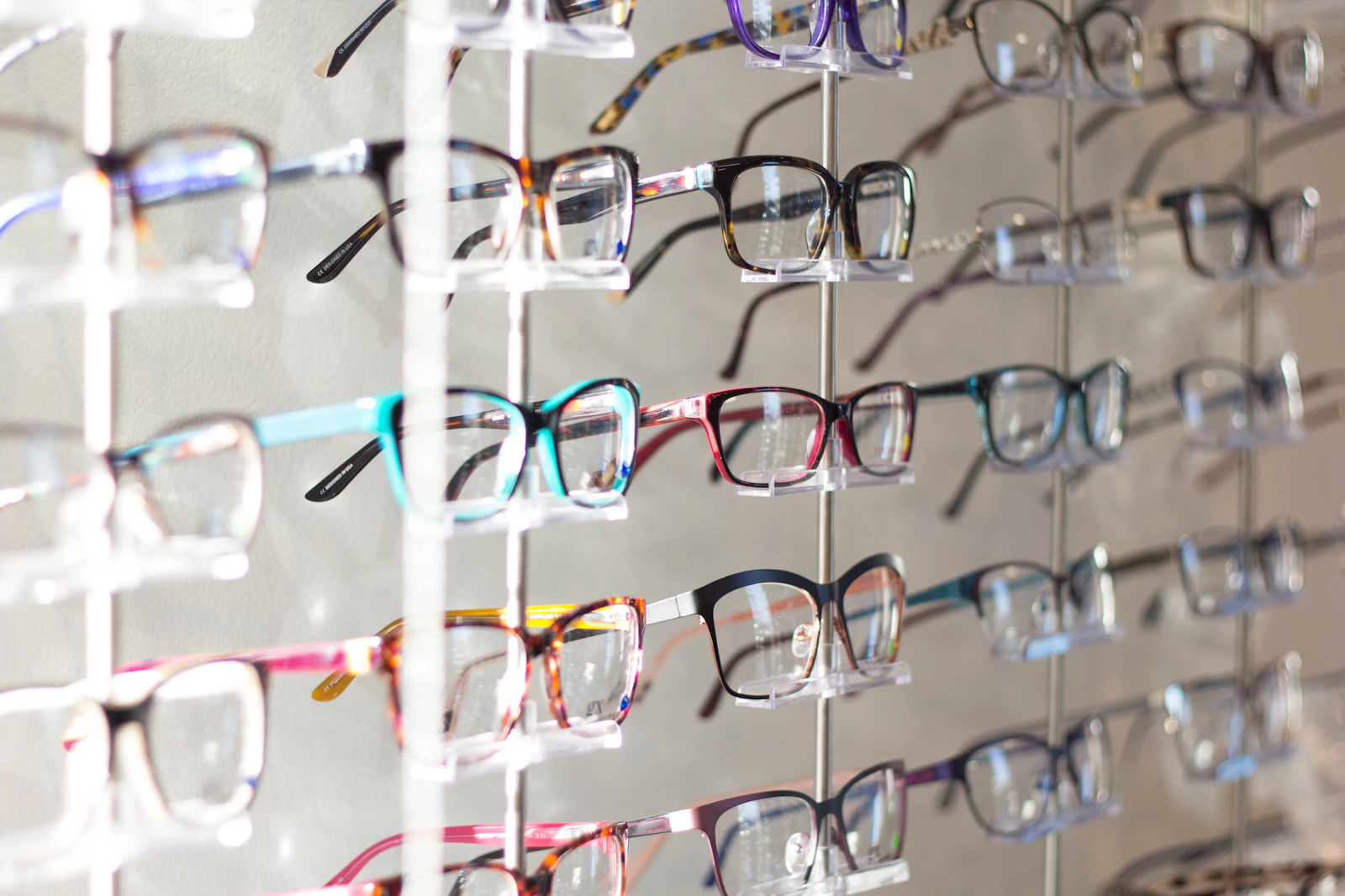 Editorial display of assorted eyeglass frames arranged on a retail rack. Photograph by Scott Van Daalen via Unsplash.