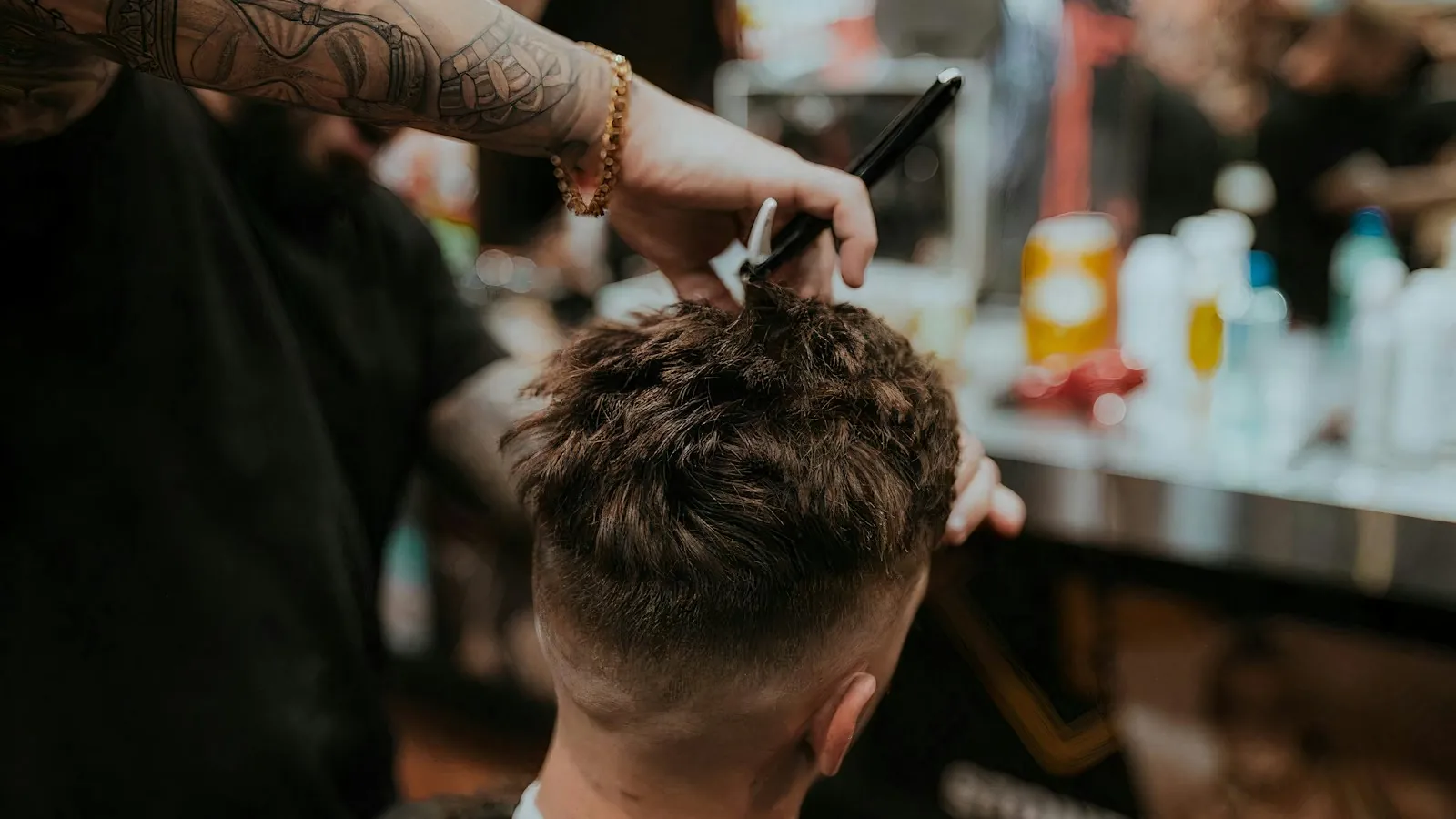 A barber giving a precise haircut in a busy shop, the customer's head turned away from the camera